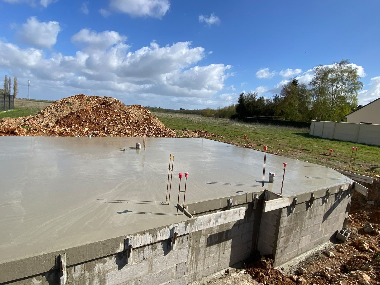 Dalle béton fraîchement coulée avec attentes d'armatures et coffrage de rive